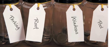 Photo of jars with money in the jars earmarked for certain categories including parking, roof, widows and pool 