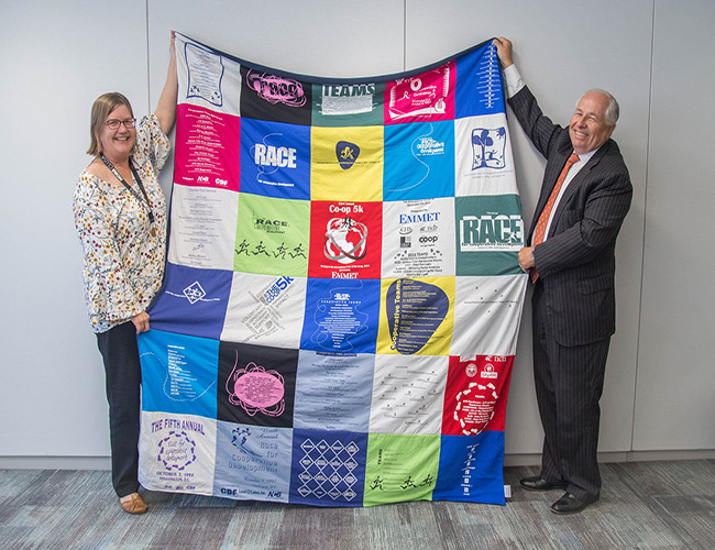 Man and Women holding a Cooperative Development Foundation quilt