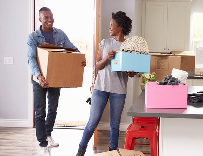 couple carrying boxes as they move into their new home