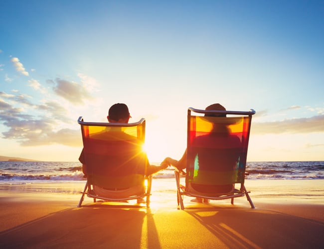 retired couple watching sunset on beach